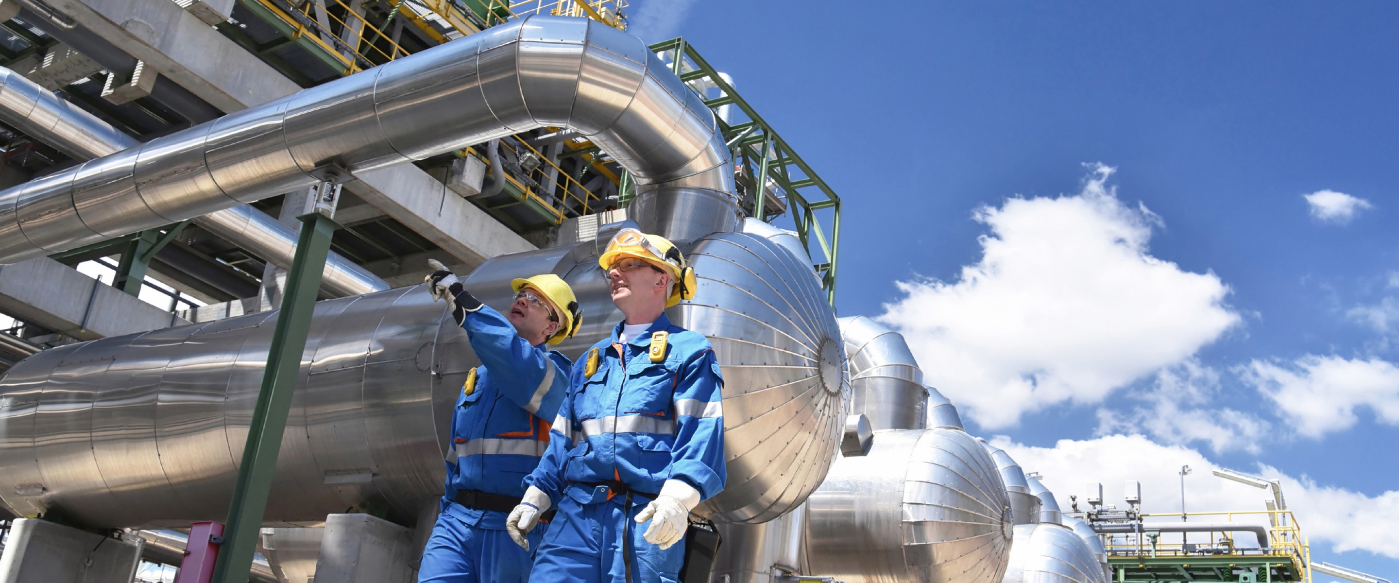 Group of industrial workers in a refinery - oil processing equipment and machinery