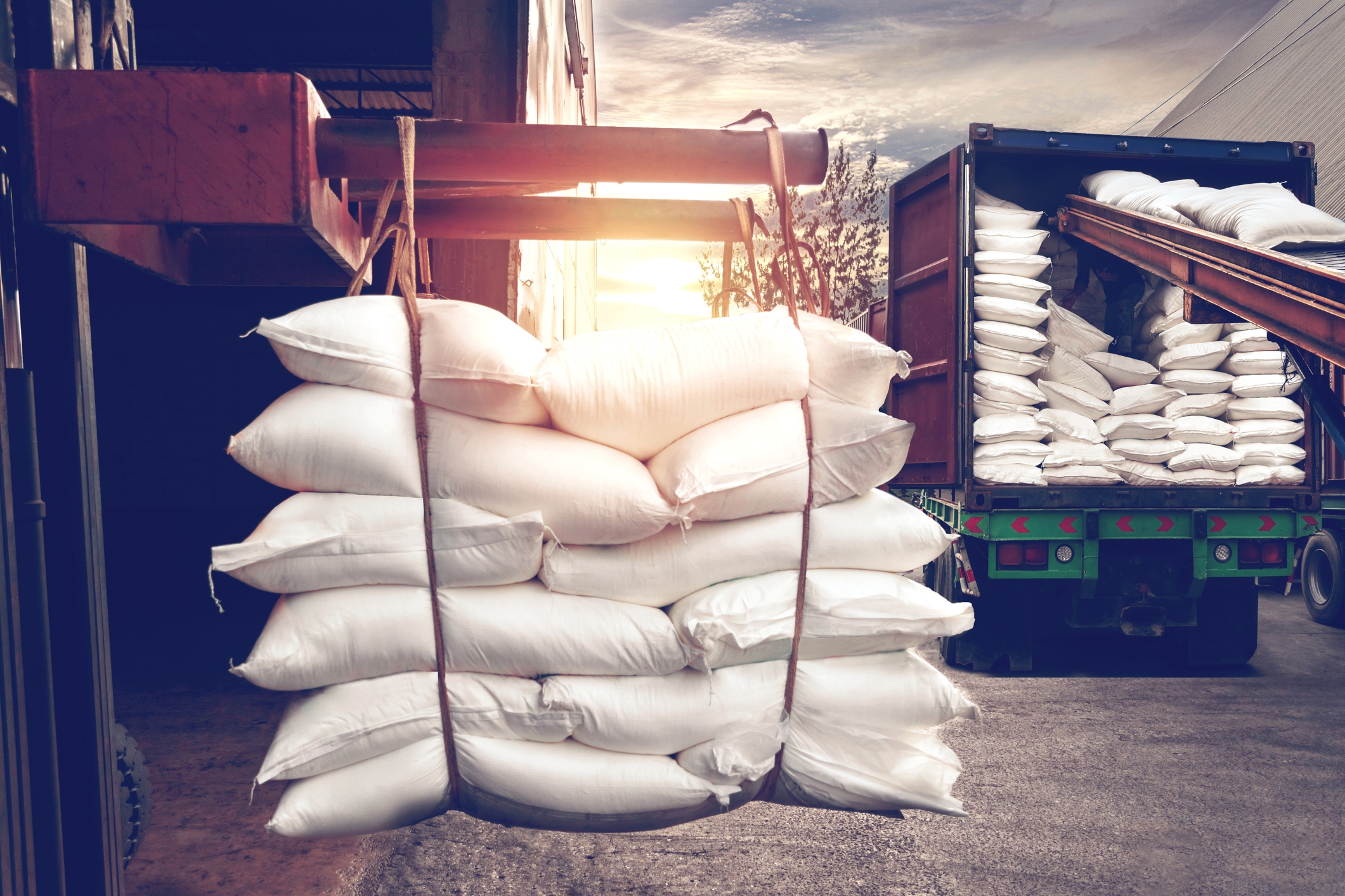 Forklift reloading white big bags into a container truck.